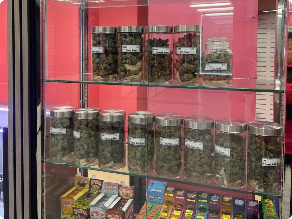 Dried flower jars lined up on glass shelves at Best Value Weed